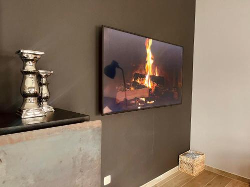 a tv hanging on a wall with a fire at Le Quatre F in La Roche-en-Ardenne