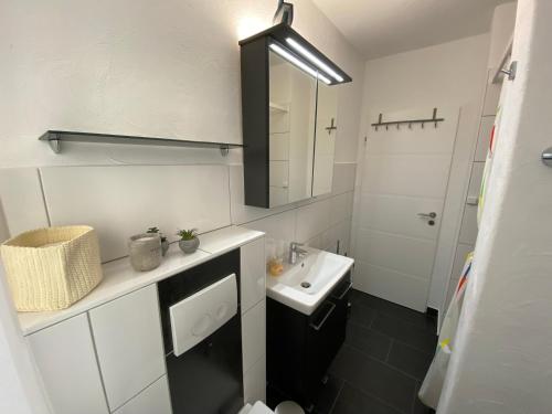 een witte badkamer met een wastafel en een spiegel bij Ferienwohnung KatzenTraum in Bad Harzburg
