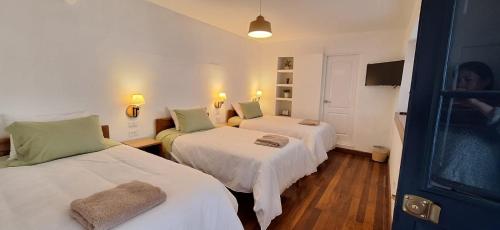 a room with two beds with white sheets and green pillows at Illa B&B in Cusco