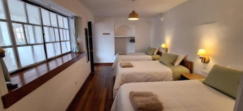 a room with two beds and a couch and windows at Illa B&B in Cusco