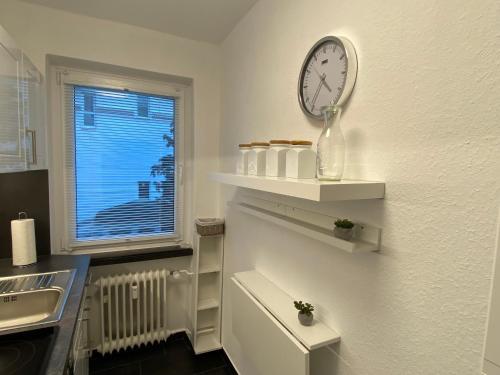 een keuken met een klok op een witte muur bij Ferienwohnung KatzenTraum in Bad Harzburg
