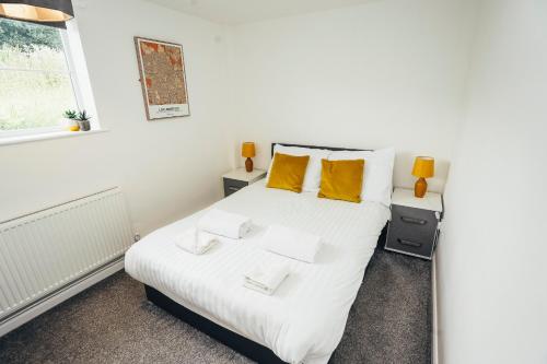 a bedroom with a white bed with yellow pillows at Cottages In Derbyshire, Oak Cottage in Hazelwood