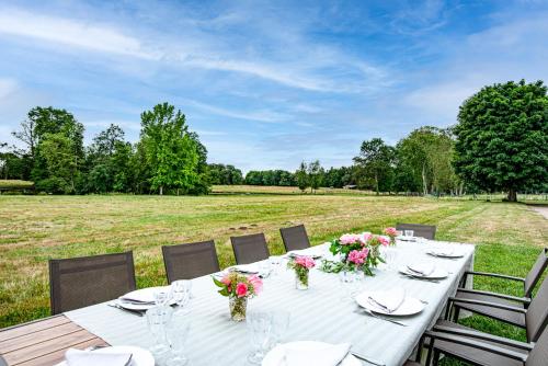 a white table with flowers on top of a field at Les Louteaux - Splendide Château du XVIII -Piscine- Parc de Lamas in Chézy