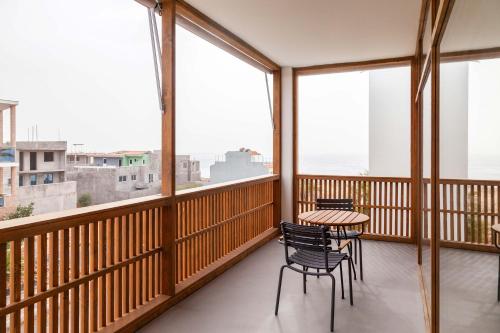 a balcony with a table and chairs and windows at King Fisher Village in Tarrafal