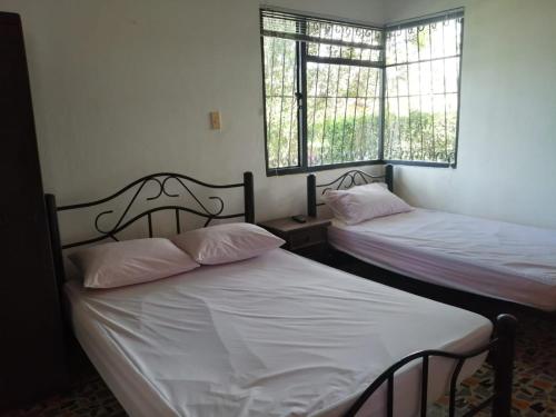 duas camas num quarto com duas janelas em Finca la sharola em Guaduala