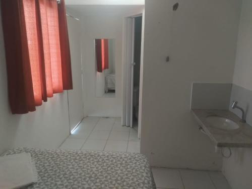 a bathroom with a bed and a sink and red curtains at Flat Beach Itamaracá - pousada FBI in Itamaracá