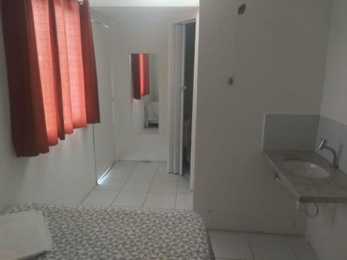 a bathroom with a bed and a sink and red curtains at Pousada fbi - Flat Beach Itamaracá in Itamaracá