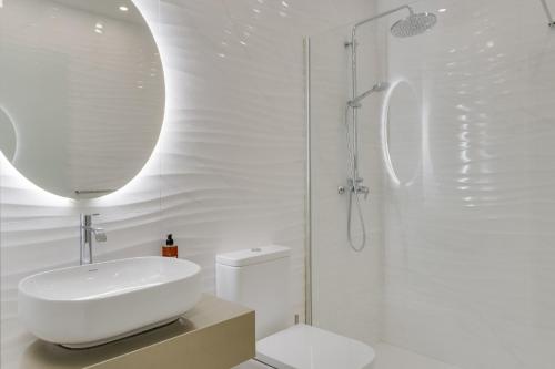 uma casa de banho branca com um lavatório e um chuveiro em Torre Palace II by Atlantic Holiday em Câmara de Lobos