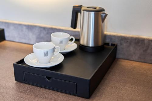 two coffee cups and a coffee pot on a black tray at WHITE HILLS HOTEL spa&sport in Uzhhorod