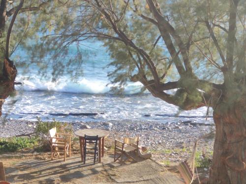 a table and chairs next to a beach with the ocean at Georgoshouse Lykos beach Sfakia in Livanianá