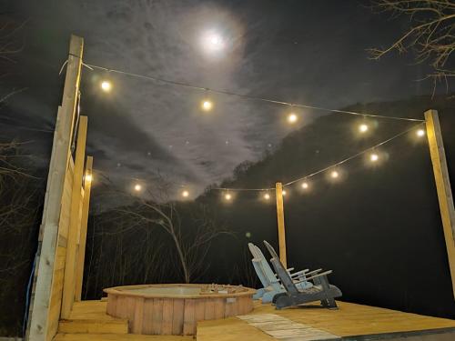 a deck with chairs and a hot tub at night at Bungalow Casa Corbilor in Stăneşti