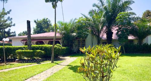 a house with a green yard with palm trees at Sunset Hotel Entebbe in Entebbe