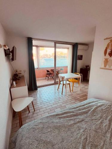une chambre avec un lit, une table et des chaises dans l'établissement ALHAMBRA Joli studio piscine proche plage Richelieu Cap d'Agde, au Cap d'Agde