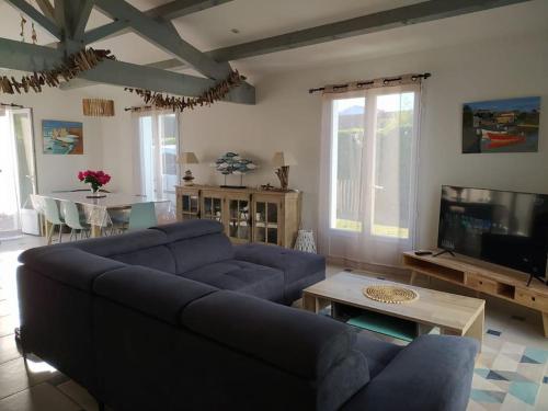 a living room with a blue couch and a tv at Maison de vacances : Bord de mer in Saint-Pierre-dʼOléron