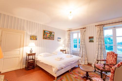 a bedroom with a bed and a chair and a window at Les Louteaux - Splendide Château du XVIII -Piscine- Parc de Lamas in Chézy
