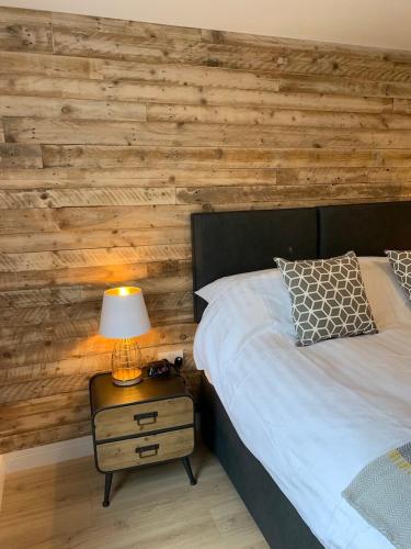 a bedroom with a wooden wall with a bed and a lamp at **Luxury one bedroom flat** in Oxford