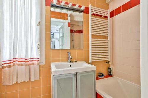 une salle de bain avec un lavabo, un miroir et une baignoire dans l'établissement calme et verdure à Paris, à Paris