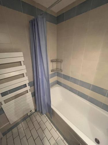 La salle de bains est pourvue d'une baignoire blanche et d'un rideau de douche bleu. dans l'établissement Atlante15, à Le Touquet-Paris-Plage
