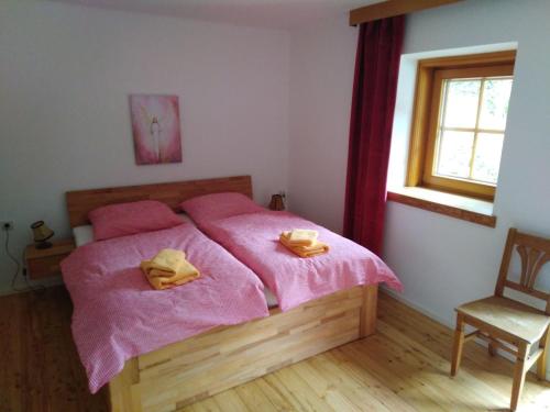 a bedroom with a bed with pink sheets and a chair at Alpengasthof Gutenbrunn in Mallnitz