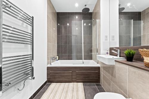 倫敦的住宿－Battersea Penthouse Sleep 9 WH，带浴缸、盥洗盆和卫生间的浴室
