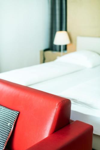 a red chair in a bedroom with a bed at Hotel Aurora in Merano