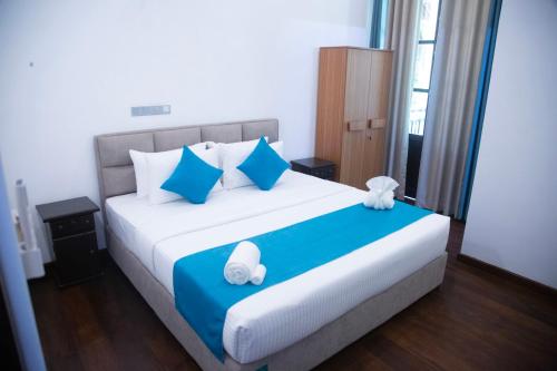 a bedroom with a large bed with blue and white pillows at Even Beach Resort in Waikkal