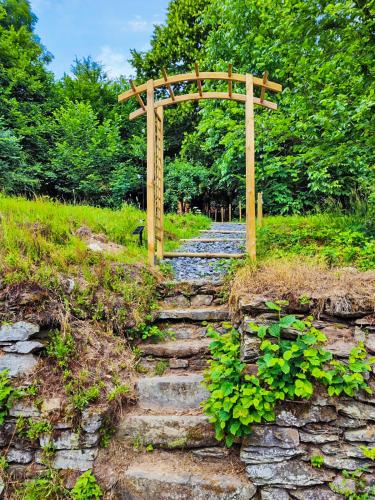 a stone path with a wooden arch over a stone path at La mini maison du Lama in Libin