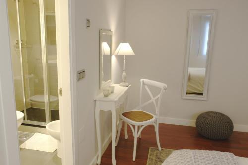 biała łazienka z krzesłem i lustrem w obiekcie Tranquilo y Céntrico apartamento 1 dormitorio w Maladze