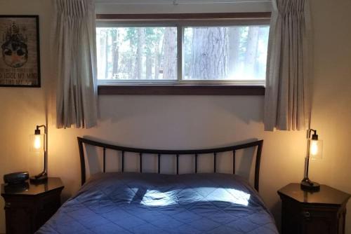 a bedroom with a bed and a window and two lamps at Mountain Life On Deck in Arnold