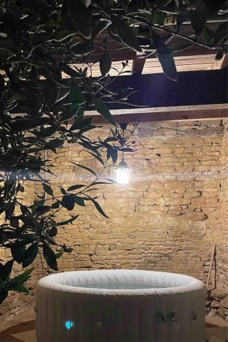 un arbre devant un mur de briques avec une baignoire dans l'établissement Dependance De Charme Avec Jacuzzi Saint Andr Le, à Saint-André-le-Désert