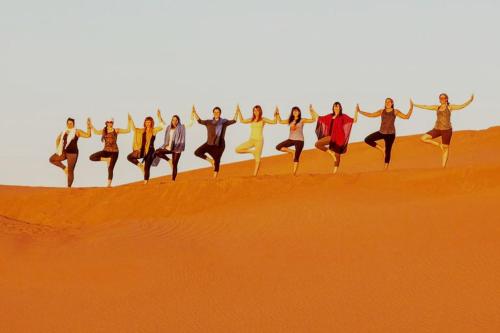 a group of people jumping in the desert at Overnight Camp Erg Chebbi in Merzouga