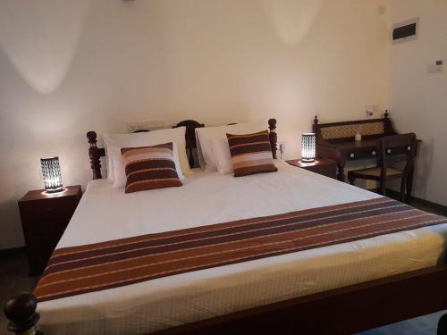 a bedroom with a large bed with pillows and a desk at Villa one in Balapitiya