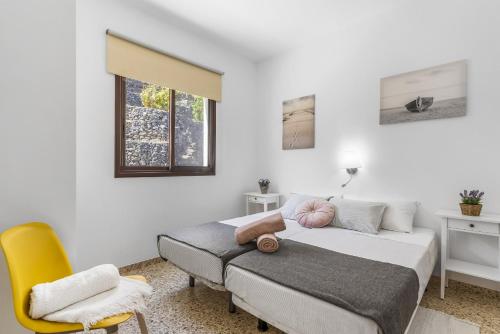 a bedroom with a bed and a yellow chair at Central Penthouse, close to the Natural pools with Big terrace, ocean & city view in Garachico