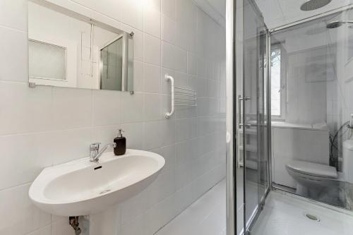 uma casa de banho branca com um lavatório e um chuveiro em CityRooms Sopot em Sopot