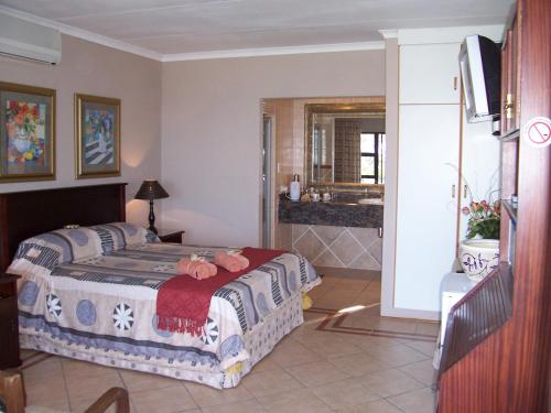 a bedroom with a bed and a bathroom at Birdcage B&B in Amanzimtoti