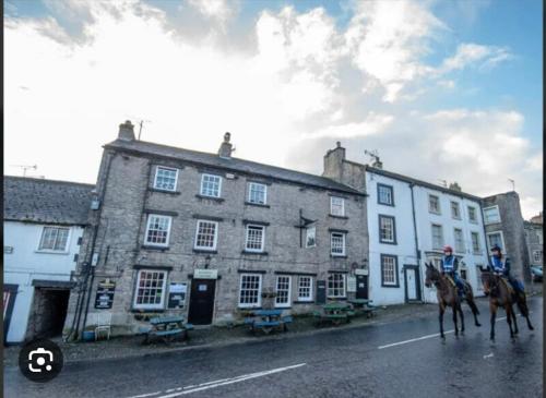 two people on horses in front of a building at The Dante arms in Middleham