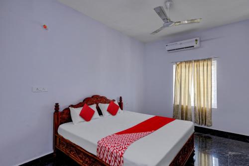 Un dormitorio con una cama con almohadas rojas y una ventana en OYO JDR GARDENS, en Tirupati