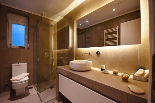 Un baño con lavabo, inodoro y espejo. en Zarmine Villa, en Parga