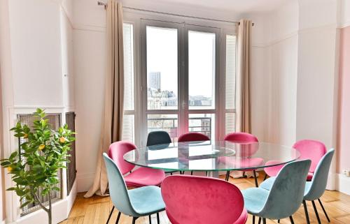 une salle à manger avec une table en verre et des chaises roses dans l'établissement Appartement luxueux Porte Maillot - Neuilly -II, à Neuilly-sur-Seine