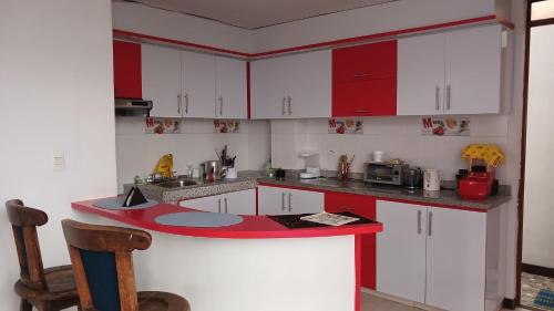 una cucina con armadi bianchi e piano di lavoro rosso di Hotel Boutique Arandano Azul a Paipa