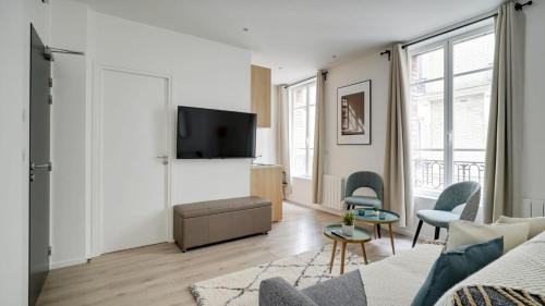 a living room with a couch and a tv at 154 Suite Phil - Superb apartment in Paris in Paris