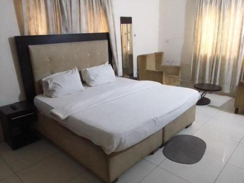 um quarto com uma cama grande com lençóis brancos e almofadas em St Theresers apartments lodge4 em Lagos