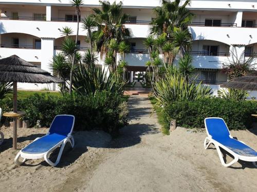 two beach chairs and an umbrella on the sand in front of a hotel at Casa Johanna, plage et piscine in Moriani Plage
