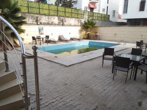 a swimming pool with tables and chairs next to a building at St Theresers apartments lodge4 in Lagos