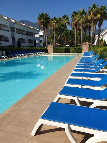 a row of blue lounge chairs in a swimming pool at Casa Johanna, plage et piscine in Moriani Plage