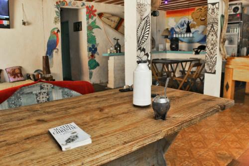 uma mesa de madeira com um vaso e um livro sobre ele em Raizes Surf and Bar Hostel em Búzios