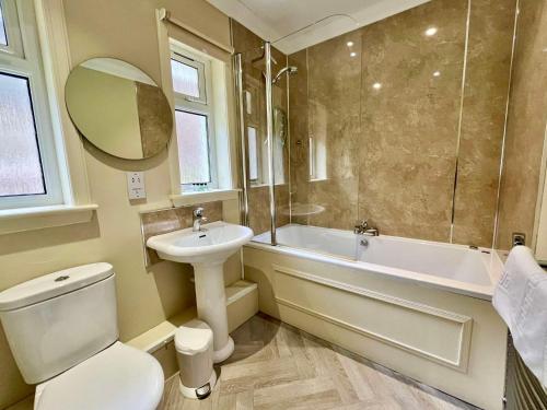 een badkamer met een toilet, een wastafel en een bad bij Glenachulish Bay with Hot Tub in Glencoe