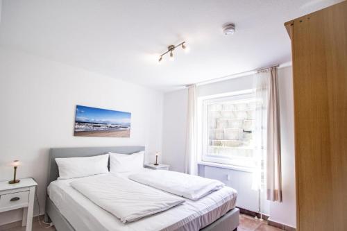 ein weißes Schlafzimmer mit einem Bett und einem Fenster in der Unterkunft Ahrendt- Haus Cäcilia  in Wenningstedt-Braderup