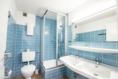 ein blau gefliestes Bad mit WC und Waschbecken in der Unterkunft Ahrendt- Haus Cäcilia  in Wenningstedt-Braderup
