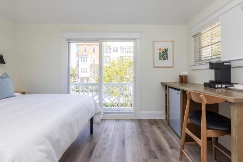 een slaapkamer met een bed, een bureau en een raam bij The Princess Anne 200 Inn at Old Beach in Virginia Beach